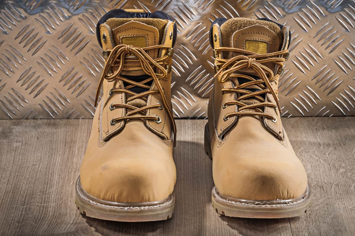 waterproof and durable work boots on wooden board with corrugated metal plate in the background