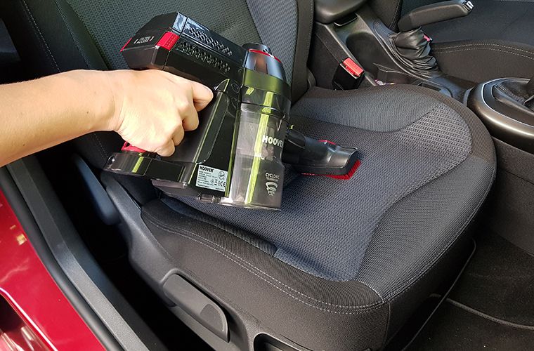 Vacuuming a car seat with a battery vacuumer