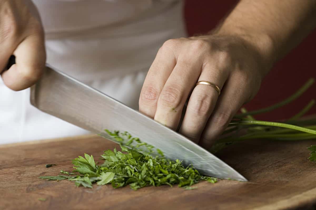 Chef chopping parsley on a wooden board
