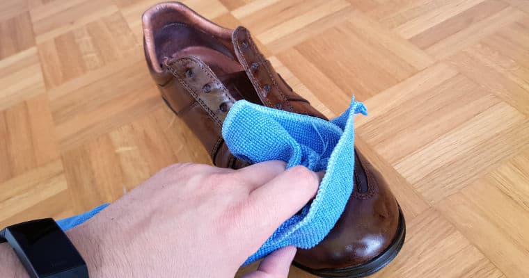 cleaning a brown leather shoe with a damp cloth