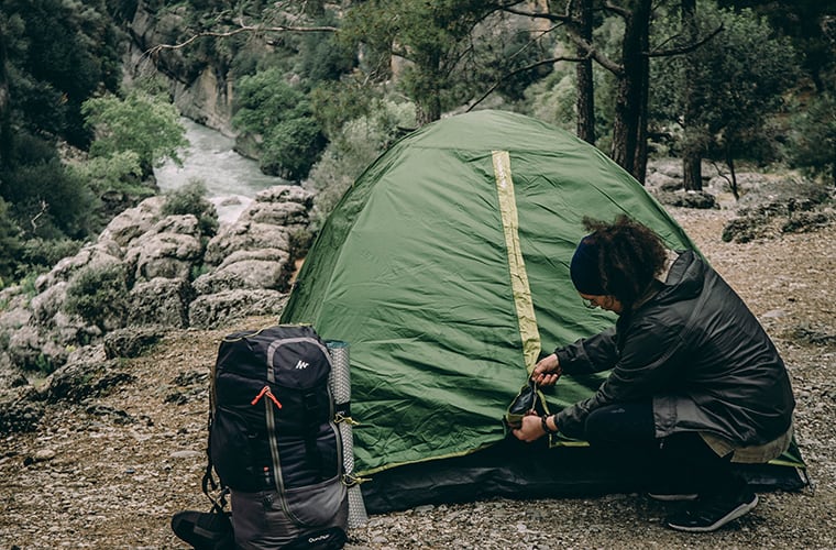 woman setting up a tent in the wilderness