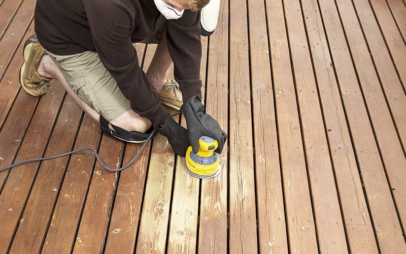 Man performing maintenance on home wooden deck