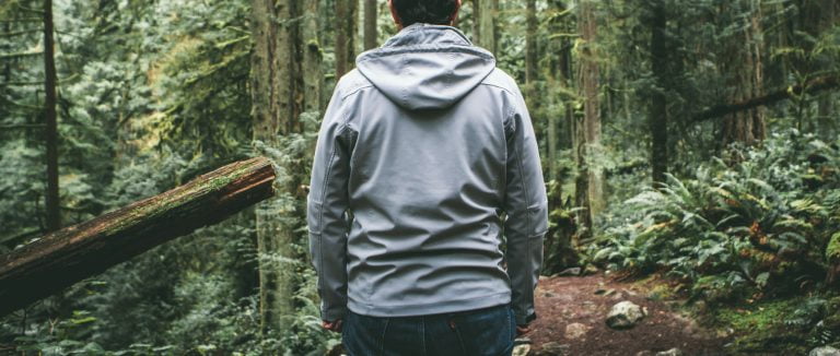 man standing in the woods with a gray hoodie