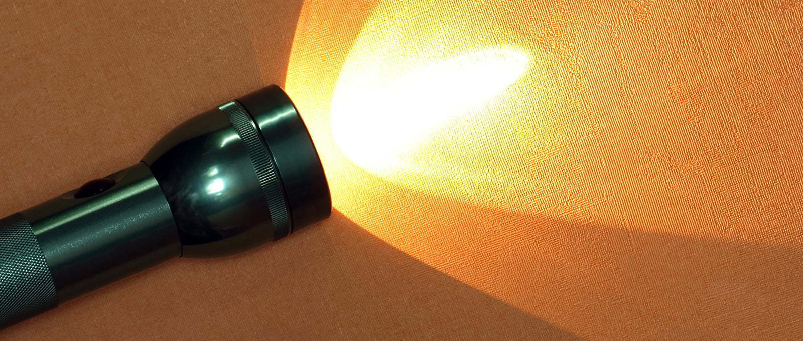 Modern aluminium luminous flashlight on ginger background with copy space
