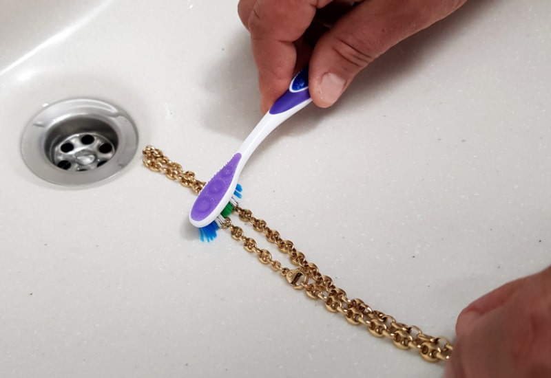 cleaning a gold chain with a toothbrush