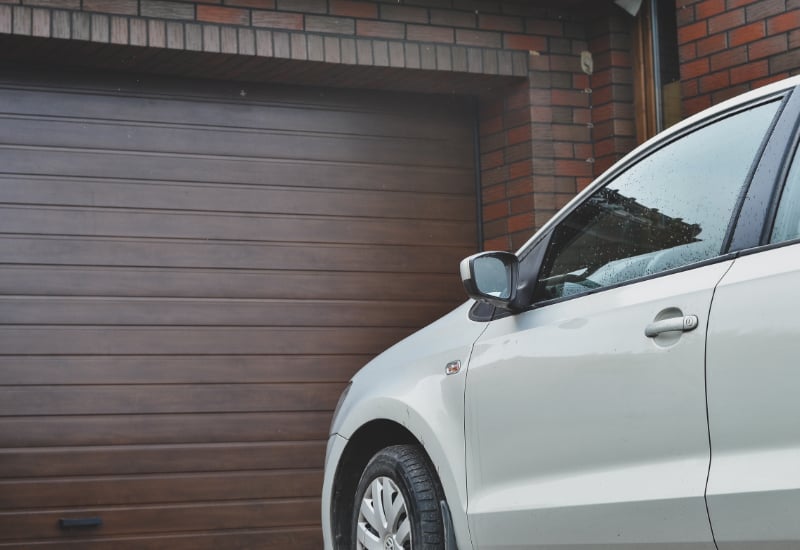 Part of a car parked in front of the garage door