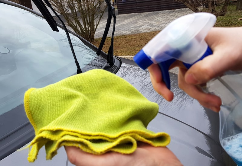 spraying window cleaner on a microfiber cloth
