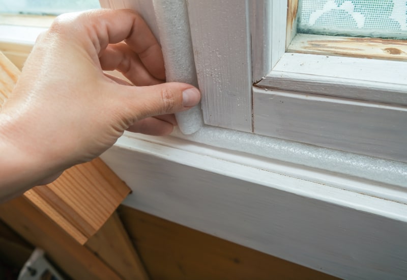 Woman hand insulating old windows