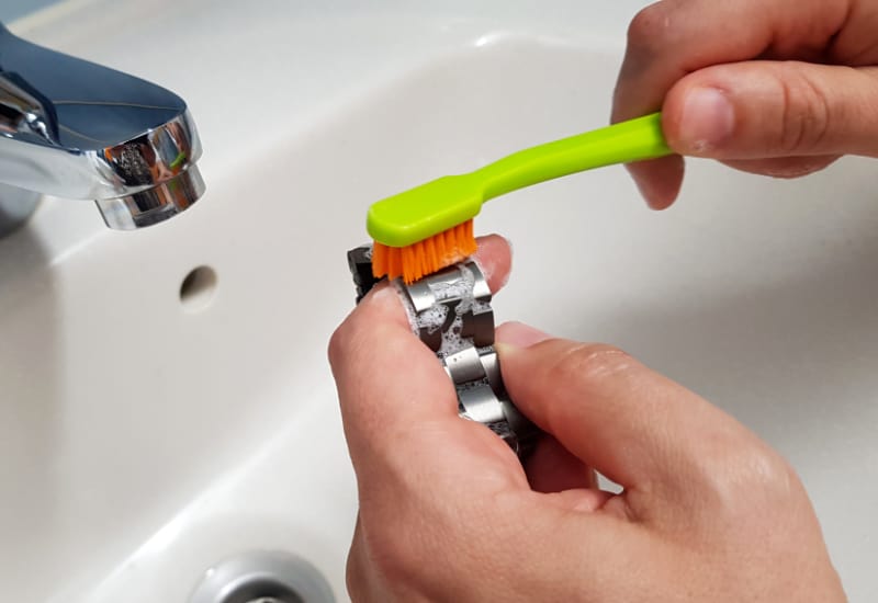 Cleaning metal watch band links with a toothbrush