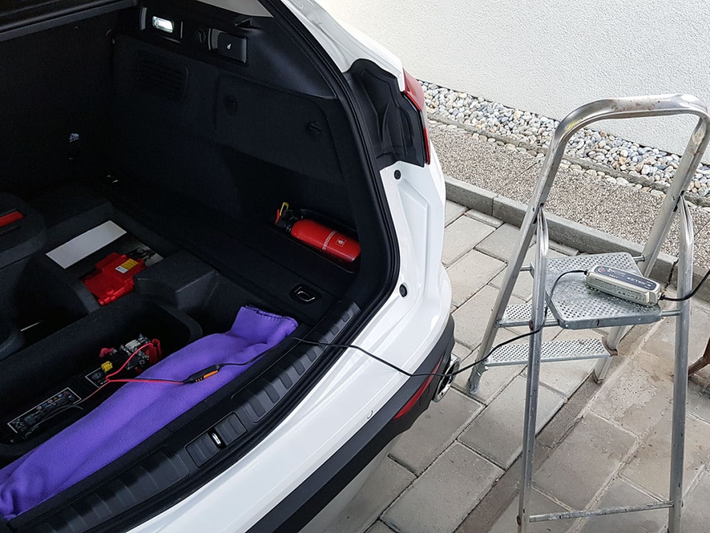 A CTEK MXS 5.0 charger put on a ladder, charging a white Alfa Romeo Stelvio MY2019