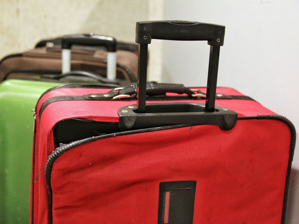 Torn suitcase with other luggage